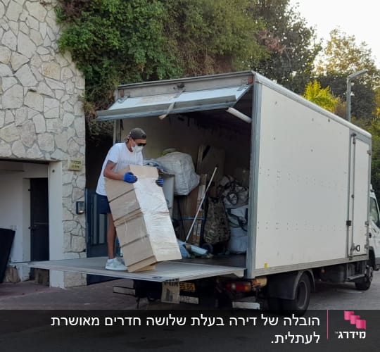 אדם מעמיס קרטון למשאית הובלה פתוחה